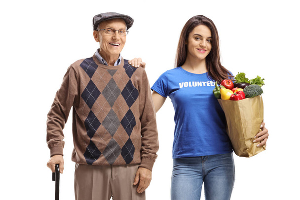 Elderly man and a female volunteer carrying his shopping bag isolated on white background - Fotografie, Obrázek