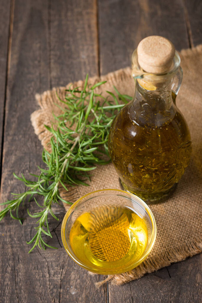 Rosemary oil on wooden background. Natural food concept.  - Foto, afbeelding