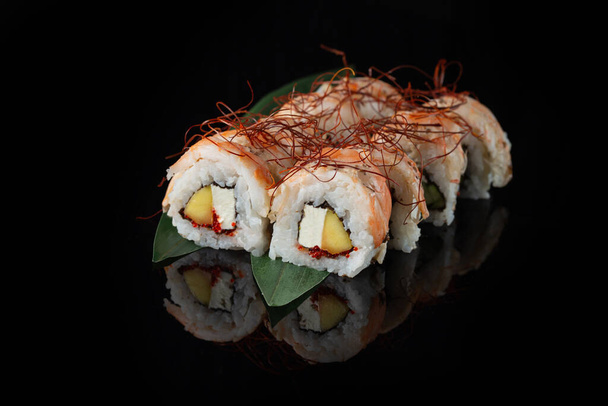 Tradycyjne pyszne świeże sushi roll zestaw na czarnym tle z odbiciem. Sushi z ryżem, nori, serem śmietankowym, kawiorem tobiko, awokado. Menu z sushi. Japońska kuchnia, restauracja. Żywność azjatycka - Zdjęcie, obraz