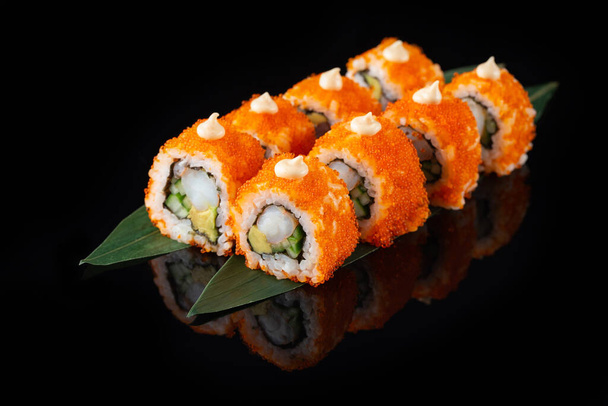 Hagyományos ízletes friss sushi tekercs, fekete háttérrel, elmélkedéssel. Sushi tekercs rizzsel, norival, krémsajttal, tobiko kaviárral, avokádóval. Sushi menü. Japán konyha, étterem. Ázsiai élelmiszer - Fotó, kép