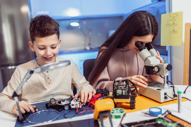 顕微鏡を使って自宅でロボットを作る子供たち。家庭でのロボット教育. - 写真・画像