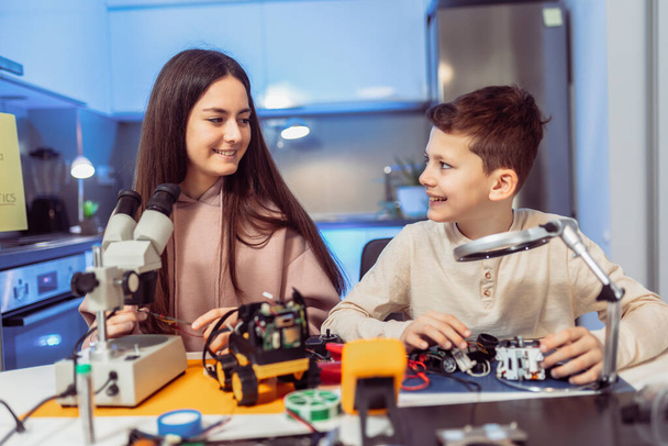 Bambini che fanno un robot a casa usando il microscopio. Educazione in robotica a casa. - Foto, immagini