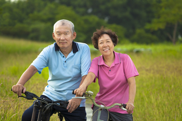 Ζευγάρι χαρούμενος ασιατικές ηλικιωμένους ποδήλατο στο πάρκο. - Φωτογραφία, εικόνα