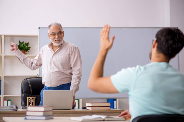 Öreg férfi tanár és fiatal férfi diák az osztályteremben - Fotó, kép