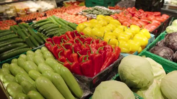 Sok különböző zöldség van kiállítva a boltban. Élelmiszer-kiskereskedelem a szupermarketben. A kamera sima serpenyője. - Felvétel, videó