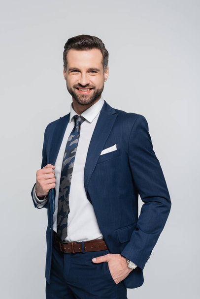 happy and successful businessman standing with hand in pocket isolated on grey - Fotografie, Obrázek
