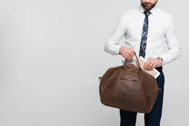 cropped view of economist putting folder into leather briefcase isolated on grey - Foto, Imagem