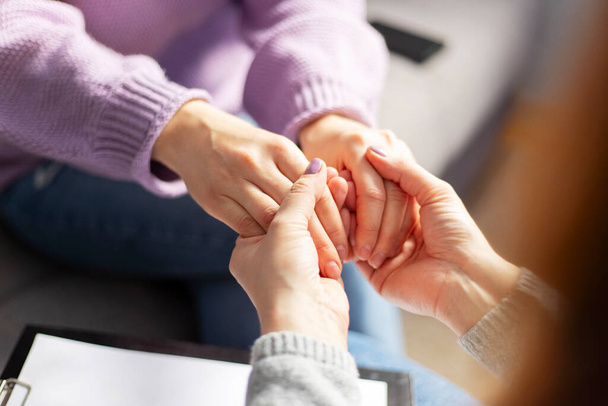 Detailní záběr psycholožky držící ženy za ruce během terapie. Psychoterapeut podporující její depresivní pacientku. - Fotografie, Obrázek