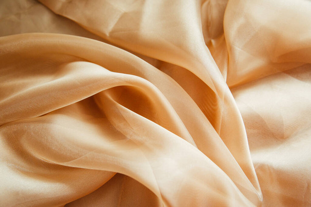 Golden fabric for drapery. A piece of cloth with folds. - Photo, image