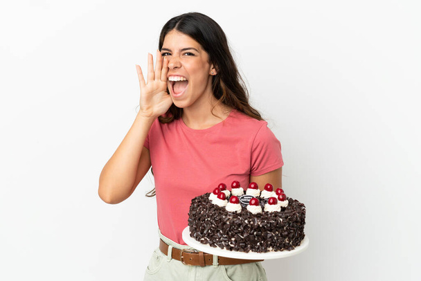 jonge Kaukasische vrouw houden verjaardag taart geïsoleerd op witte achtergrond schreeuwen met mond wijd open - Foto, afbeelding