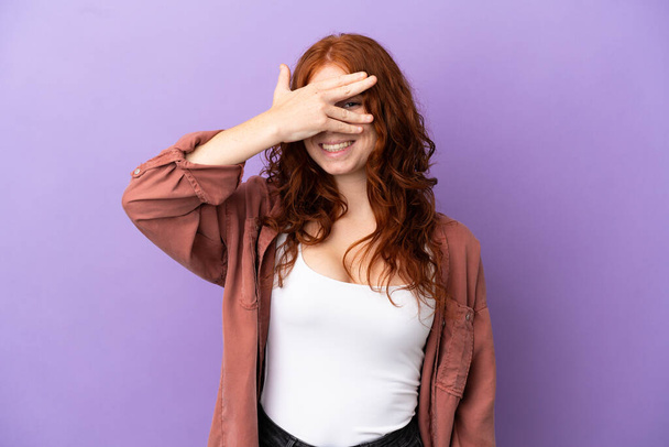 Teenager zrzka dívka přes izolované fialové pozadí zakrývající oči rukama a s úsměvem - Fotografie, Obrázek