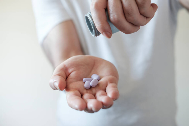 Правий чоловік тримає таблетки під пляшкою таблеток. Фіолетові таблетки
. - Фото, зображення