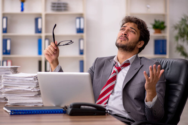 Fiatal férfi alkalmazott elégedetlen a túlzott munka az irodában - Fotó, kép
