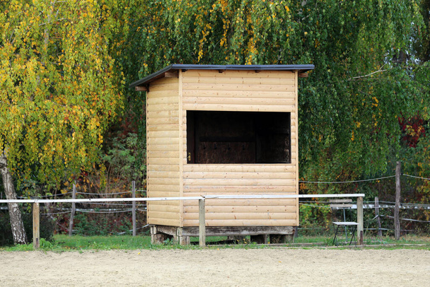 Foto di un'arena equestre coperta di sabbia con casa in legno per giudici all'aperto estate - Foto, immagini