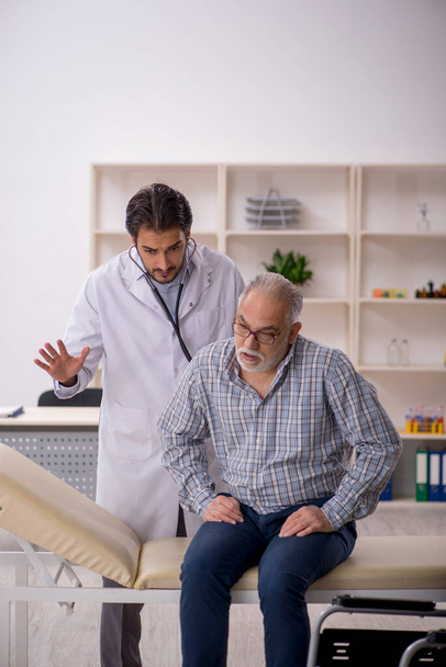 Old man in wheelchair visiting young male doctor - Photo, Image