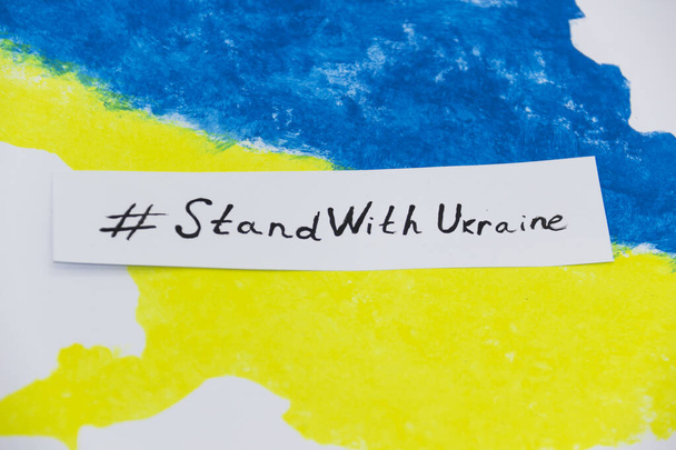 Die ukrainische Landkarte in blauen und gelben Farben mit einem Banner darauf mit den Worten STAND WITH UKRAINE. - Foto, Bild