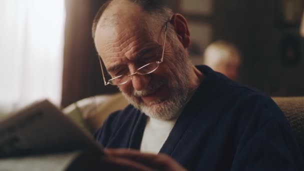 Abuelo leyendo un periódico en el sofá - Metraje, vídeo