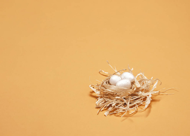 A simple spring concept. Small white eggs in a bright nest. - Zdjęcie, obraz