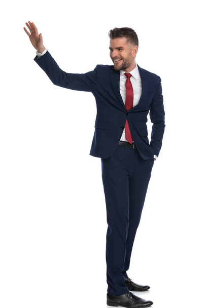 young attractive businessman turning around to salute someone with a warm smile on his face - Fotoğraf, Görsel