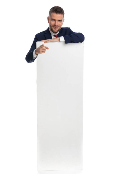 üzletember mutat a kamera hátulról egy üres hirdetőtábla fehér háttér - Fotó, kép