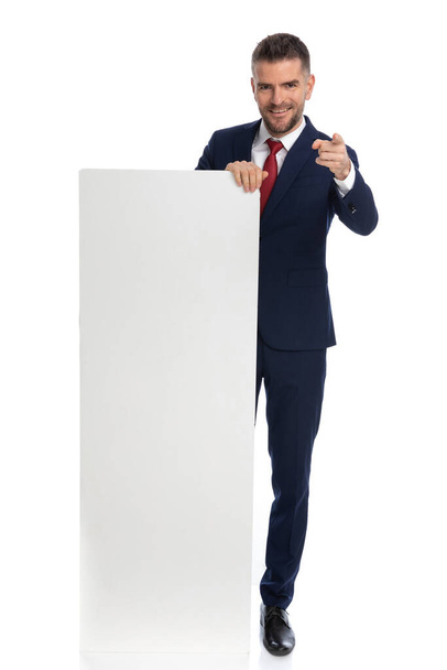 young businessman gesturing you where picked for the advertisement against white background - Fotó, kép