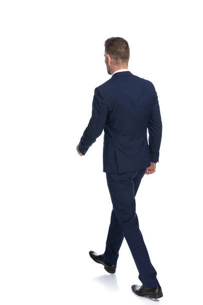 rear view of a businessman walking on his way to the path of life against white studio background - Foto, Bild