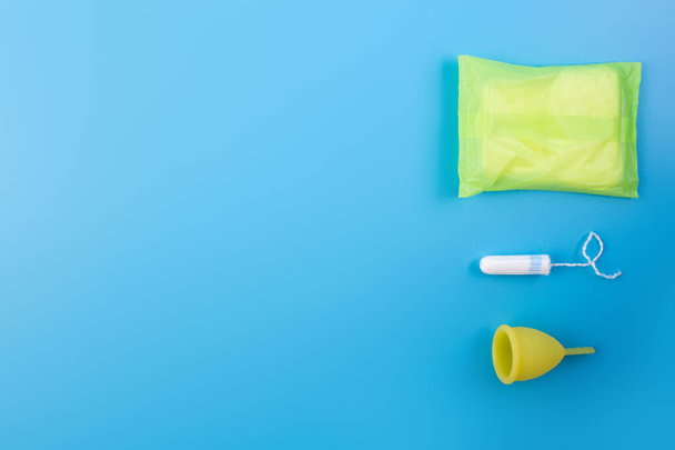 Copo menstrual amarelo de silicone com almofadas e tampão. Saúde das mulheres e higiene alternativa em um fundo rosa flat lay. eco-friendly, produto reutilizável Alternativa para a higiene feminina. Minimalismo. - Foto, Imagem