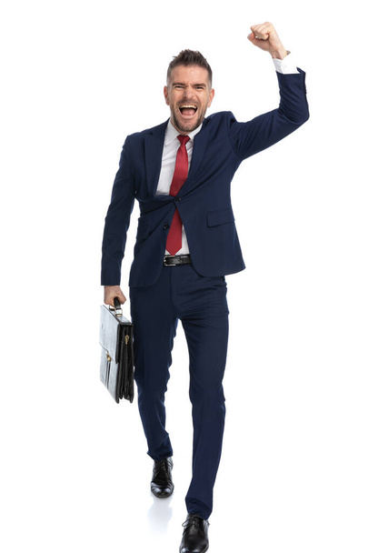 επιχειρηματίας που έρχεται από την εργασία και γιορτάζει την επιτυχία με μια υπόθεση στο χέρι του και ένα χέρι επάνω - Φωτογραφία, εικόνα