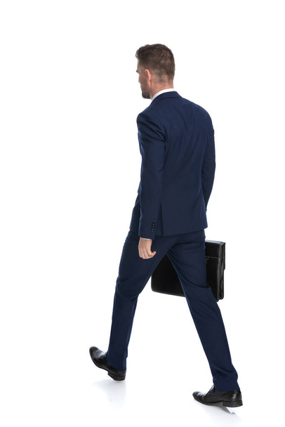 zadní pohled na podnikatele kráčejícího do práce se svým případem v jedné ruce proti bílému pozadí - Fotografie, Obrázek