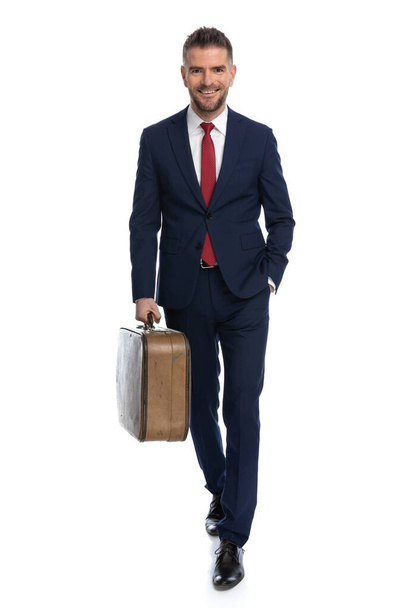 homem de negócios atraente caminhando em direção à câmera, com sua bagagem pronta para algum tempo fora - Foto, Imagem