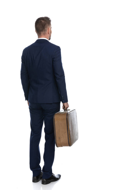 Rückansicht eines Geschäftsmannes, der mit seinem Gepäck auf seine Abholung wartet, um in den Urlaub zu fahren - Foto, Bild