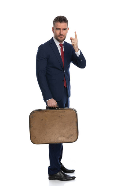 sexy businessman gesturing pay attention and holding a luggage with him for his trip  - Fotoğraf, Görsel