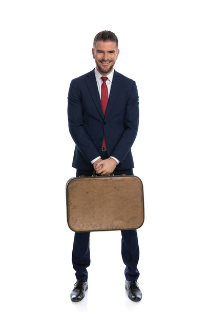 sexy businessman feeling happy to go on a vacation and holding his luggage with a smile on his face - Foto, Imagem