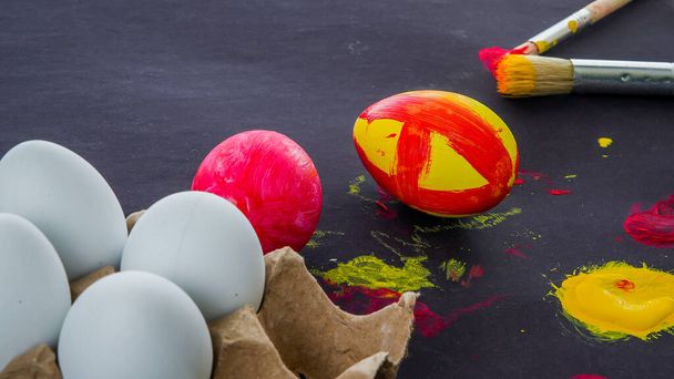 Покраска пасхальных яиц на черном фоне с сопливым пространством - Фото, изображение