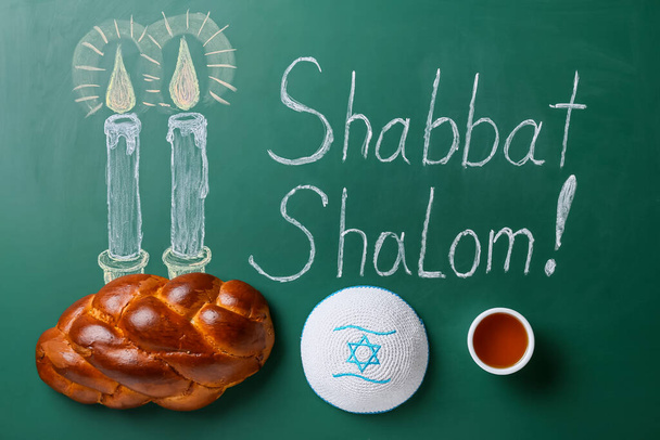 Нарисовал светящиеся свечи и надпись SHABBAT SHALOM с традиционным хлебом хала и еврейской шапкой на доске - Фото, изображение