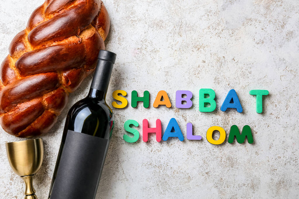 Tradycyjny chleb chała z butelką wina i tekst SHABBAT SHALOM na tle grunge - Zdjęcie, obraz