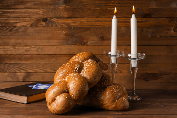 Parlayan mumlarla geleneksel challah ekmeği ve ahşap arka planda Tevrat. Şabat Şalom - Fotoğraf, Görsel