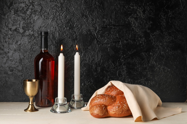 Традиционный хлеб халла с вином и светящимися свечами на тёмном фоне. Шалом, Шаббат - Фото, изображение
