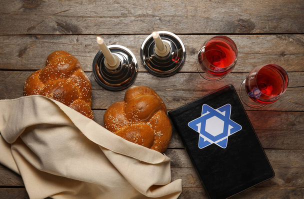 Torah with traditional challah bread, glasses of wine and candles on wooden background. Shabbat Shalom - Photo, Image
