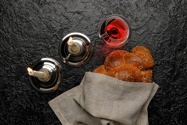 Traditional challah bread with glass of wine and candles on dark background. Shabbat Shalom - Photo, Image