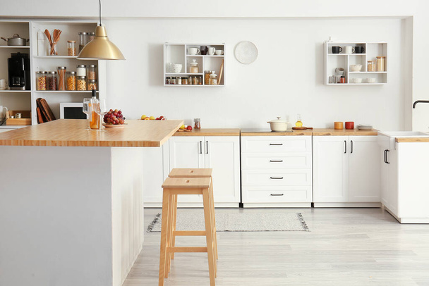 Innenraum der hellen modernen Küche mit weißen Arbeitsplatten, Regalen und Lebensmitteln - Foto, Bild