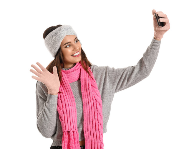 Young woman in warm gloves taking selfie on white background - Foto, immagini