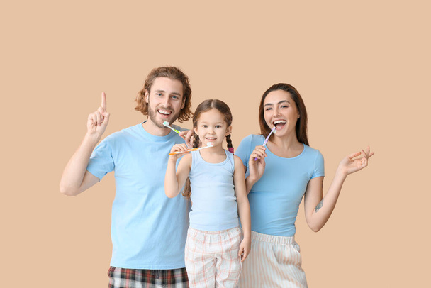 Bambina con i suoi genitori lavarsi i denti su sfondo beige - Foto, immagini