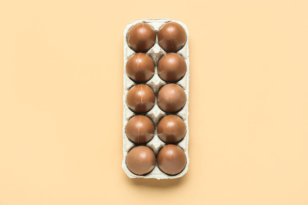 Holder with delicious chocolate eggs on beige background - Photo, Image