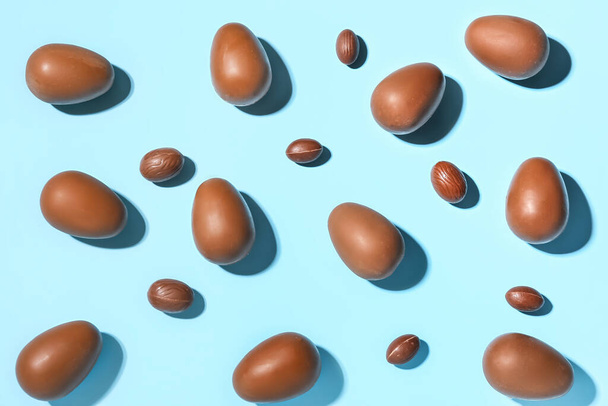 Delicious chocolate eggs on blue background - Foto, Imagen