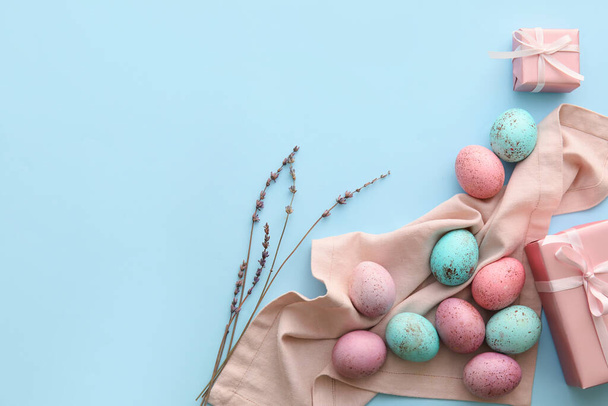 Painted Easter eggs, willow branches and gift boxes on blue background - Photo, Image