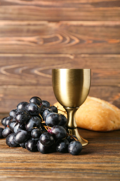 Beker wijn met druiven en brood op houten ondergrond - Foto, afbeelding
