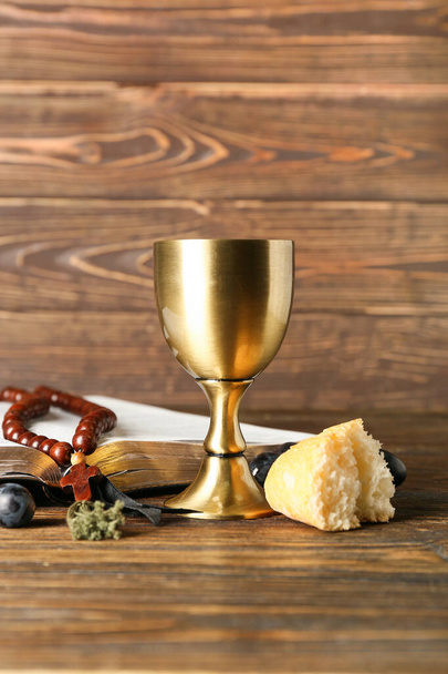 聖書とワインのカップ,木製の背景にロザリオとパン - 写真・画像
