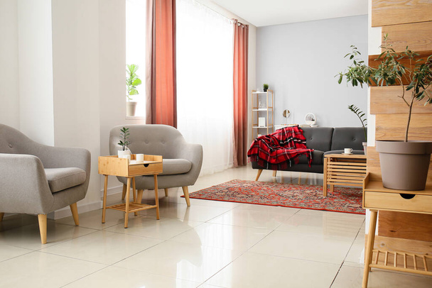 Інтер'єр затишної вітальні з вінтажним килимом, кріслами та столами
 - Фото, зображення