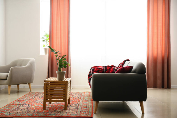 Інтер'єр затишної вітальні з вінтажним килимом, столом і диваном
 - Фото, зображення